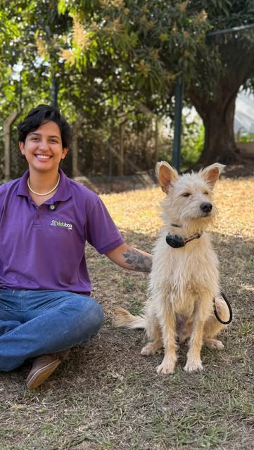 Colaboradora da Vida Boa Pet sentada ao lado de um cachorro no gramado